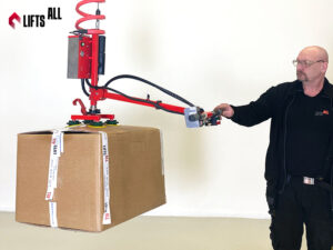 Warehouse worker using a LiftsAll vacuum lifter to handle boxes safely and ergonomically.